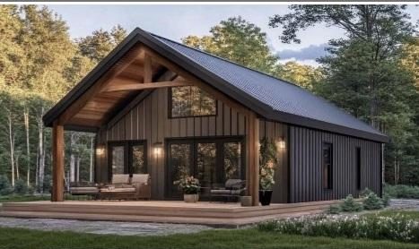 A dark gable cabin with a timber porch and black metal cladding